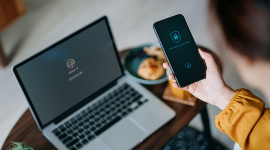 Woman holding mobile phone with security software to help protect against smishing 1100x550